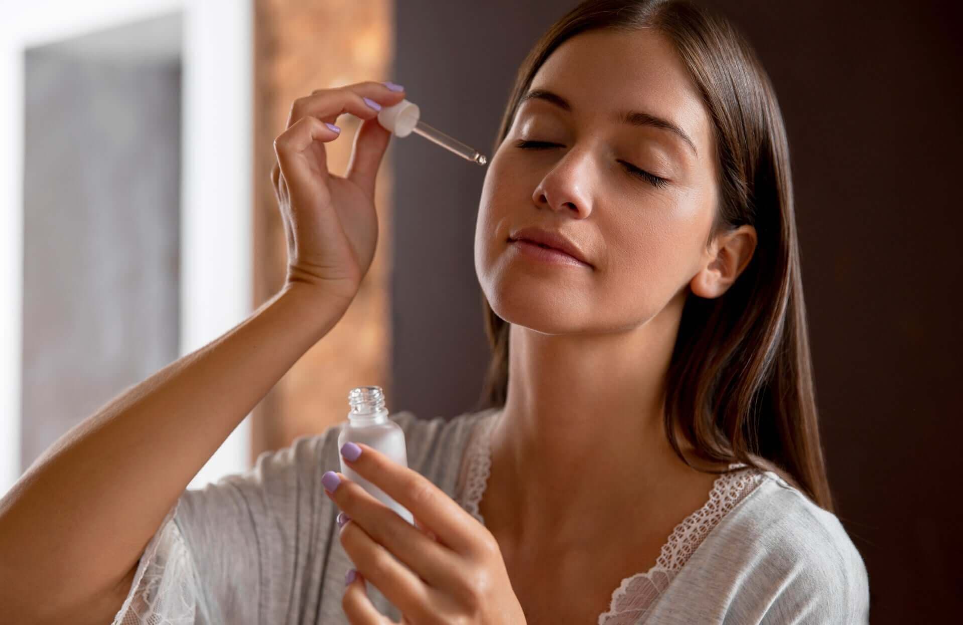 Mulher serena aplicando sérum facial com conta-gotas